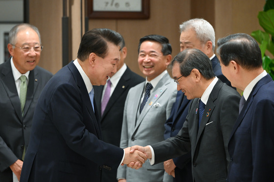 President Yoon Suk Yeol, left, shakes his hand with Japan Business Federation Chairman Masakazu Tokura at the presidential office in central Seoul on Friday. [PRESIDENTIAL OFFICE]