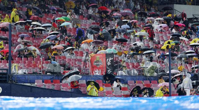 21일 광주 기아챔피언스필드에서 열린 2024 KBO 포스트시즌 한국시리즈 1차전 삼성 라이온즈와 KIA 타이거즈의 경기 중 6회초 우천으로 경기가 중단된 뒤에도 야구팬들이 자리를 지키고 있다. 연합뉴스