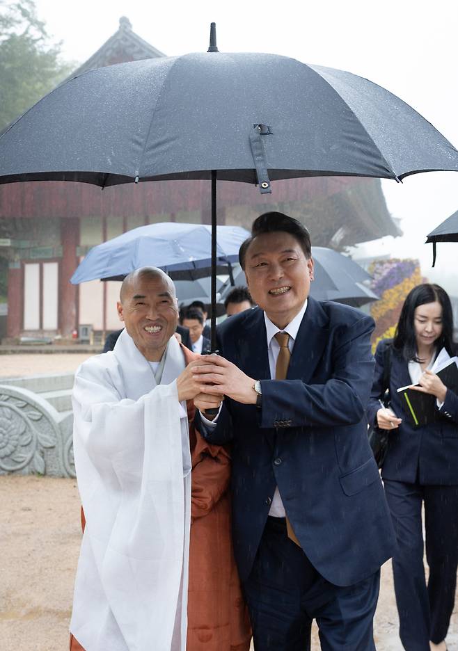 윤석열 대통령이 22일 부산 금정구 범어사를 찾아 대웅전 참배 뒤 주지 정오스님과 함께 우산을 쓰고 주지실로 이동하고 있다.  / 사진=대통령실 제공