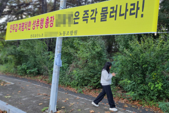 대전 유성구 한 사립대학 총장과 부총장이 동료 여교수를 상대로 추행·폭행했다는 의혹이 불거진 가운데 23일 한 학생이 총장을 규탄하는 내용의 현수막 인근을 지나가고 있다. 김민 기자.