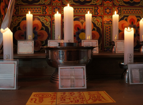 Shaman Kwon Soo-jin lights candles and writes talismans for her clients at her shrine. Kwon's life as a shaman and as an ordinary girl was filmed over seven years in documentary movie "A Girl Who Dreams About Time" (2023). [KIM JU-YEON]