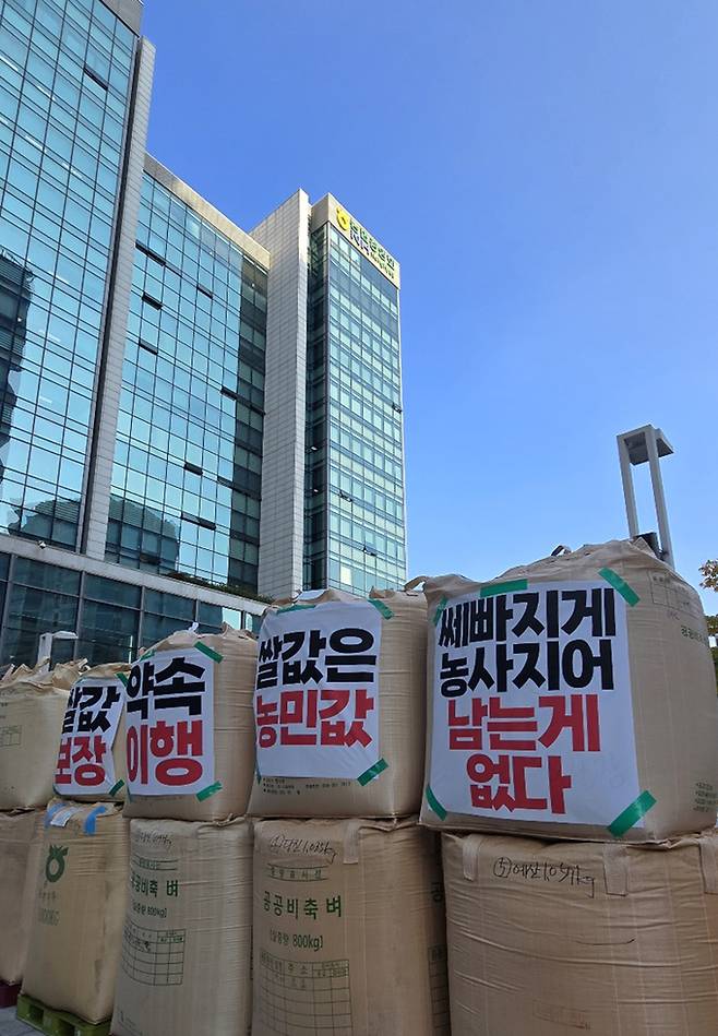 전국농민회총연맹(이하 ‘전농’)과 전국쌀생산자협회가 24일 오후 서울 농협중앙회 본관 앞에서 기자회견을 열고 나락값 7만원 공약 이행 등 즉각적인 쌀값 안정화 대책마련을 촉구하는 가운데 관계자들이 나락포대에 항의 문구를 붙이고 있다.
