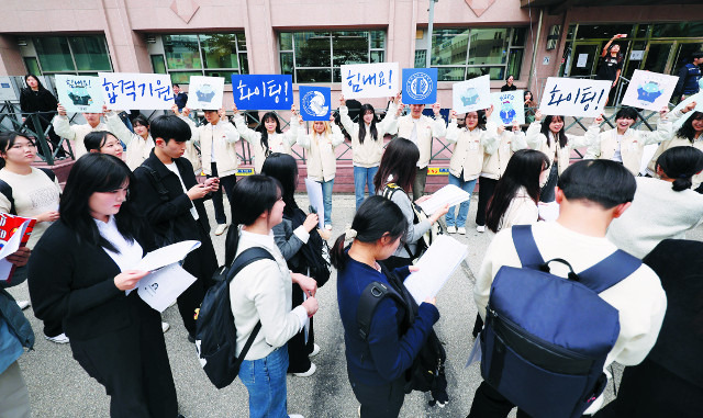 수험생들이 27일 서울 동대문구 한국외국어대학교에서 진행된 2025학년도 수시모집 학생부종합전형의 면접고사장 앞에서 순서를 기다리고 있다. 대기 줄 뒤에서 대학 재학생들이 ‘합격 기원’ 문구를 들고 수험생들을 응원하고 있다. 뉴시스