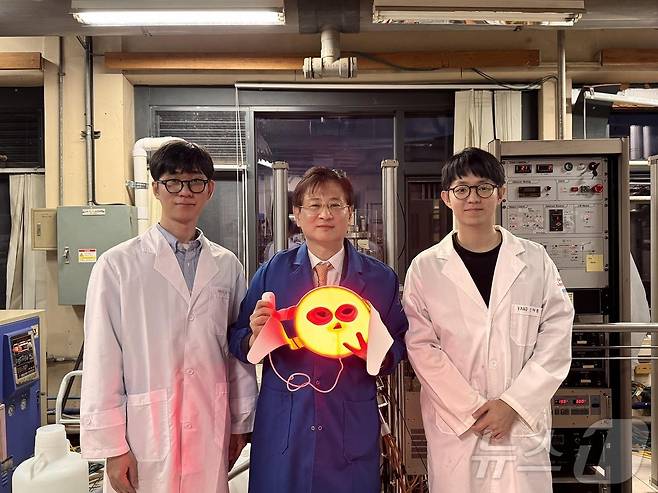 왼쪽부터 KAIST 신소재공학과 김민서 석·박사 통합과정, 이건재 석좌교수, 안재훈 박사과정이 LED 마스크와 기념촬영을 하고 있다.(KAIST 제공)/뉴스1