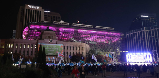 People gather for a memorial event held next to the City Hall illuminated in purple in central Seoul on Saturday. [JOINT PRESS CORPS]