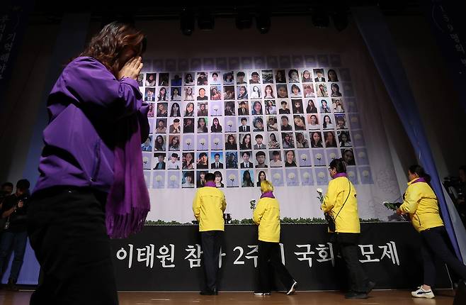 The bereaved family members of safety accidents, which include the Itaewon crowd crush, place white chrysanthemum flowers in front of the victims' photos at a memorial ceremony held at the National Assembly in Yeouido, western Seoul, on Tuesday. [JOINT PRESS CORPS]