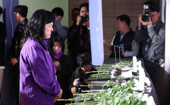 A bereaved family member of an Itaewon crowd crush victim stands in front of white chrysanthemum flowers laid for the victims at a memorial ceremony held at the National Assembly in western Seoul on Tuesday. [JOINT PRESS CORPS]