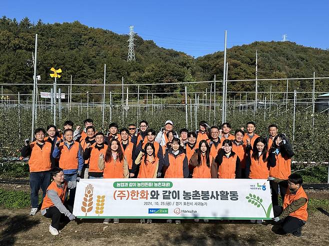 지난 25일 경기도 포천시 소재 사과 농가에서 (주)한화 임직원들이 봉사활동 시작 전 단체사진을 촬영하고 있다. 농협중앙회 제공