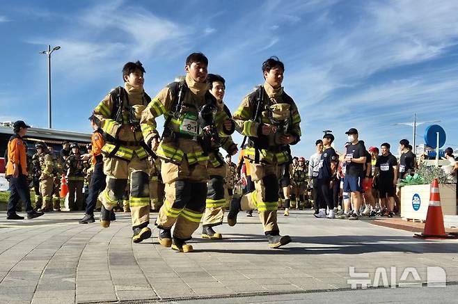 [부산=뉴시스] 김민지 기자 = 30일 오전 부산 해운대구 엘시티(LCT) 랜드마크 건물에서 열린 '전국소방공무원 해운대 LCT 계단오르기 대회' 중 단체전 부문에 참가한 소방관들이 출발선을 향해 뛰어가고 있다. 2024.10.30. mingya@newsis.com