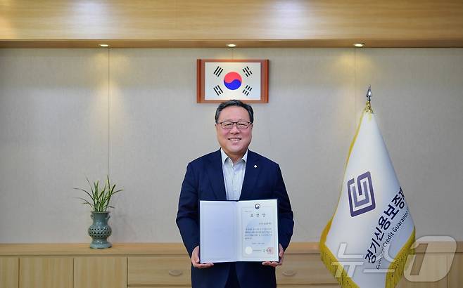 경기신용보증재단이 ‘금융발전 유공 혁신금융부문 금융위원회 위원장 표창’을 받았다. 사진은 시석중 경기신보 이사장이 표창장을 들고 있는 모습.(경기신보 제공)/