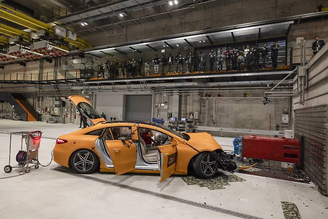 A group of Korean reporters watch as a bright orange Mercedes EQS 450 electric sedan slams into a concrete wall at Mercedes-Benz’s Vehicle Safety Technology Center in Sindelfingen, Germany on Oct. 22. (Mercedes-Benz)