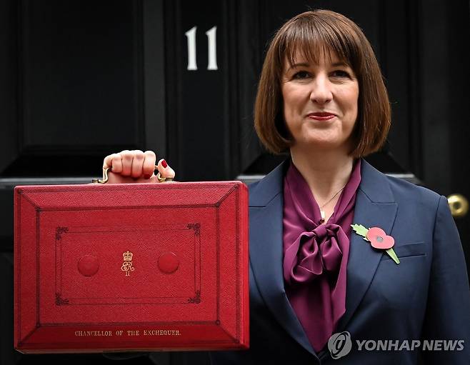 30일(현지시간) 다우닝가 11번지 앞에서 빨간 '예산 가방'을 들어올리는 리브스 재무장관 [AFP 연합뉴스]