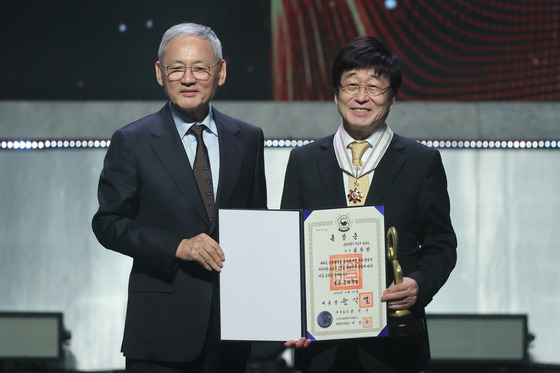 Singer-songwriter Kim Chang-wan, right, poses for a photo with Culture Minister Yu In-chon after receiving the Bogwan, or precious crown, Order of Cultural Merit during the Korea Popular Culture and Arts Awards at the National Theater's Haeoreum Grand Theater in Jung District, central Seoul, on Thursday evening. [YONHAP]