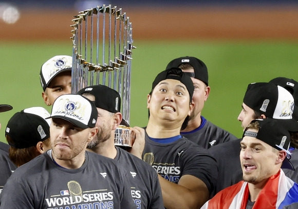 “WBC 우승보다 즐겁다” - 미국프로야구 메이저리그(MLB) LA 다저스의 오타니 쇼헤이(오른쪽 두 번째)가 31일(한국시간) 미 뉴욕 양키스타디움에서 열린 뉴욕 양키스와의 월드시리즈에서 우승이 확정된 뒤 동료와 함께 우승 트로피를 들고 기뻐하고 있다. 오타니는 지난해 일본 대표팀을 이끌고 월드베이스볼클래식(WBC) 우승을 이룬 데 이어 다저스로 이적한 첫해 월드시리즈 우승이라는 금자탑을 쌓았다. 오타니는 기자회견에서 지난해 WBC 우승과 올해 월드시리즈 우승 세리머니 중 어떤 것이 재미있었느냐는 질문에 “일본의 세리머니가 약간 차분했다면 여기서는 약간 다른 방식으로 세리머니해서 더 즐거웠다”고 답했다. 뉴욕 UPI 연합뉴스