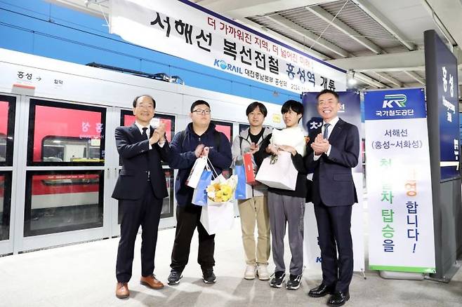 이성해 국가철도공단 이사장(왼쪽 첫 번째)과 한문희 한국철도공사 사장(오른쪽 첫 번째)이 2일 홍성역에서 서해선·장항선 첫 열차 탑승객들에게 꽃다발을 증정하고 기념 촬영을 하고 있다. / 사진제공=국가철도공단