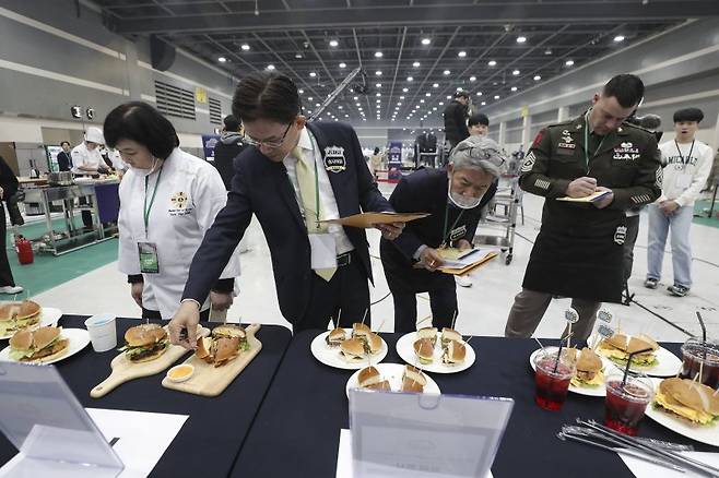 지난 2023년 11월 7일 서울 한국농수산식품유통공사에서 열린 '2023년 국제군인요리대회' 본선 경연에서 심사위원단이 '군대리아(햄버거빵) 경연' 과제로 제출된 조리 결과물을 살펴보며 심사를 하고 있다. 사진=국방일보 제공