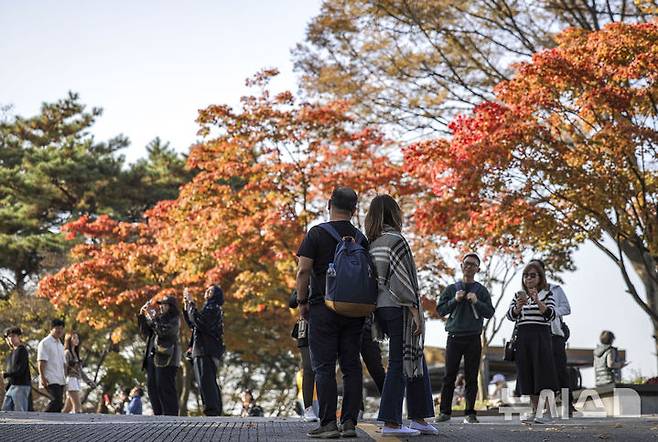 [서울=뉴시스] 정병혁 기자 = 완연한 가을 날씨를 보인 31일 서울 중구 남산을 찾은 여행객들이 울긋불긋 빛깔로 물든 단풍을 배경으로 사진찍고 있다. 2024.10.31. jhope@newsis.com