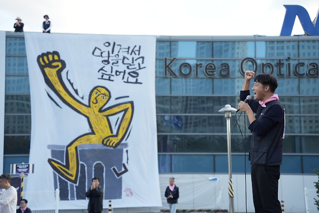 지난 2일 한국옵티칼하이테크 구미공장 건물에 “이겨서 땅을 딛고 싶어요”라는 메시지가 담긴 대형 판화가 걸려 있다. 금속노조 제공