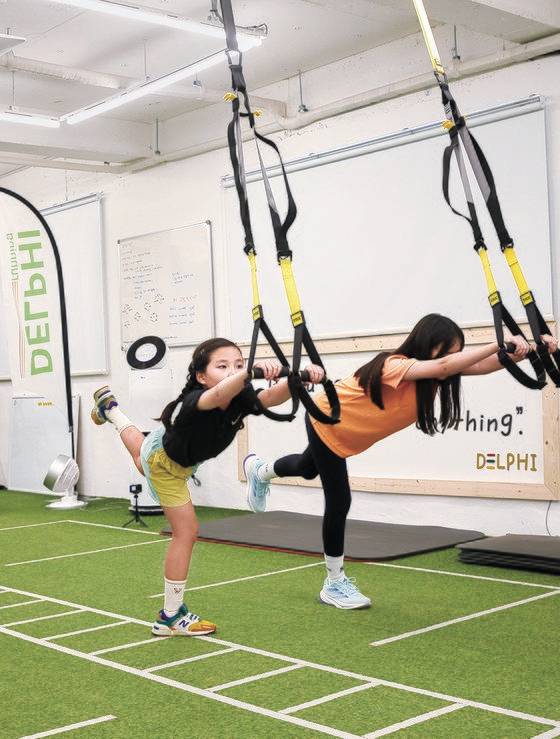 양 밴드에 각각 팔을 끼고 허리를 깊숙하게 숙인 다음 다리를 뻗는 동작을 반복한 장이안(왼쪽)·김지우 학생기자.