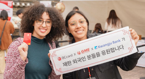 Foreign tourists visiting the Korean Folk Village in Yongin, Gyeonggi Province, on November 1 hold up mini banners prepared by BC Card, Gwangju Bank, and Global Money Express for a commemorative photo. (BC Card)