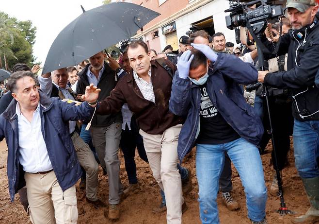 펠리페 6세 스페인 국왕(우산 속 남성)이 3일(현지시간) 발렌시아 도시 파이포르타 수해 현장을 방문한 가운데 사람들이 던진 진흙이 날아들고 있다. 연합뉴스