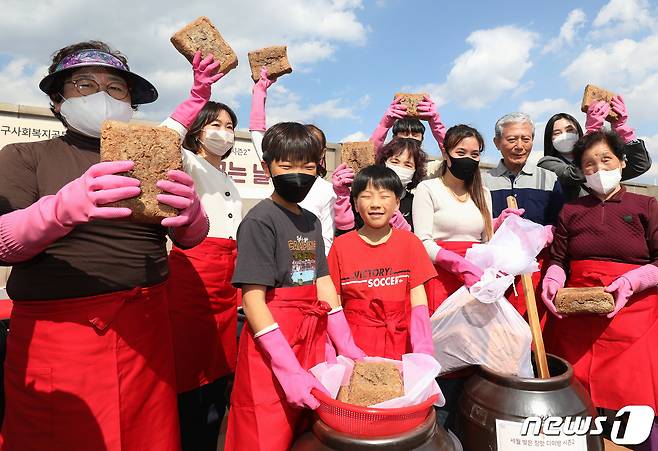 15일 오후 대구 달서구노인종합복지관 옥상에서 열린 '달서구 온(溫)가족 장(醬) 담그는 날' 행사에 참여한 어르신과 어린이, 다문화가족 등 마을주민들이 장독대에 모여 장을 담그고 있다. 2023.3.15/뉴스1 ⓒ News1 공정식 기자