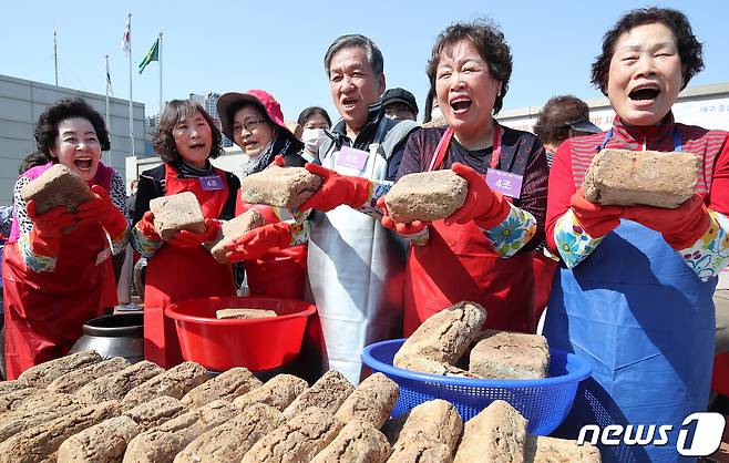 18일 오후 대구 달서구노인종합복지관 옥상에서 열린 '달서구 어르신 장(醬) 담그기' 행사에 참여한 어르신과 결혼이주여성 등 마을주민들이 장독대에 모여 장 담그기에 사용할 메주를 들어 보이며 환하게 웃고 있다. 2024.3.18/뉴스1 ⓒ News1 공정식 기자