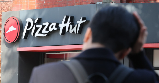 A pedestrian walks by a Pizza Hut store in Seoul on Tuesday. [NEWS1]