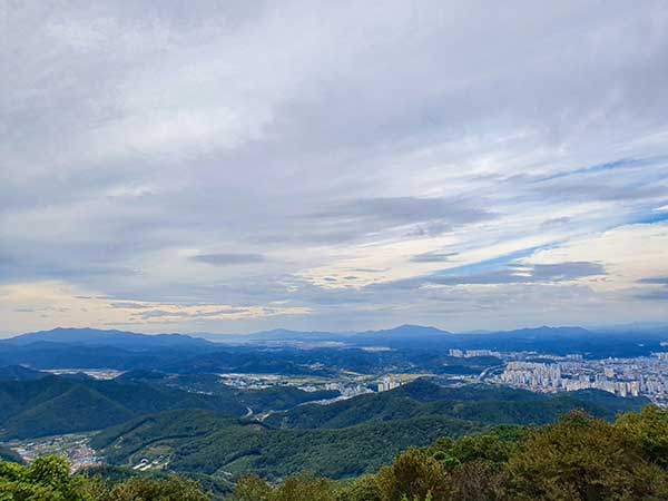 정상에서 내려다본 멀리 남해의 산들, 오른쪽 진주시가지.