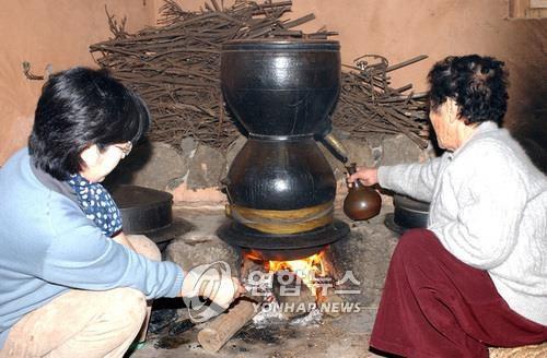 고소리술 만드는 기능보유자-전수자 제주 전통주인 오메기술과 고소리술 기능보유자 김을정(2007년 당시 83세)씨가 전수자인 며느리 김희숙(2007년 당시 48세) 씨와 함께 고소리술을 만들기 위해 '밑술'을 끓여 고소리를 통해 증류주를 받아내고 있다. /2007년 1월 23일 취재사진(홍동수 기자)