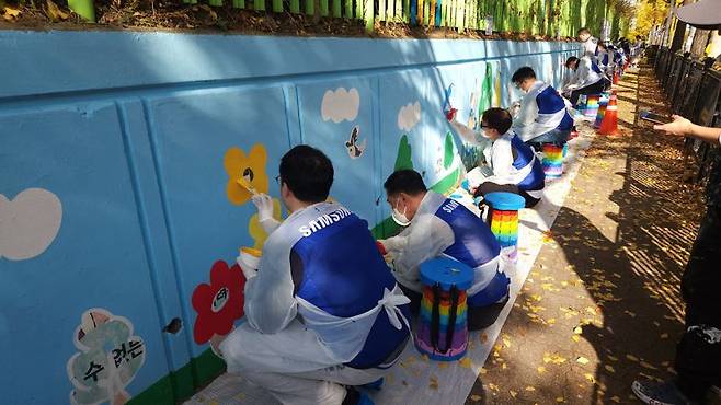 삼성전자 임직원들이 지난 12일 수원시 권선구 구운초등학교에서 벽화 그리기 봉사 활동에 참여하고 있다. 삼성 제공