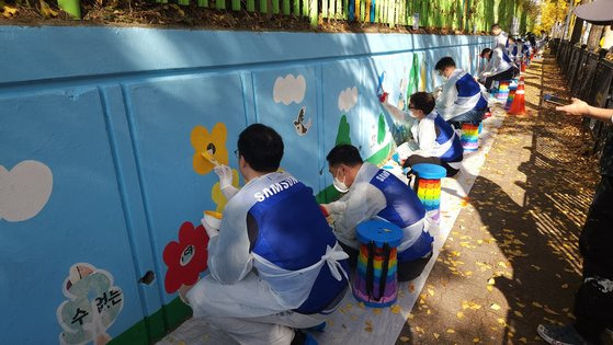 삼성전자 임직원들이 12일 수원시 권선구 구운초등학교에서 벽화 그리기 봉사 활동에 참여하고 있다. 사진 삼성