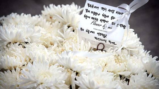 Bundles of white chrysanthemums are left near the Exit 1 of Itaewon Station in Yongsan District, central Seoul, on Nov. 28, 2022, to mourn the victims of the crowd crush tragedy that claimed 159 lives on the night of Oct. 29. [NEWS1]