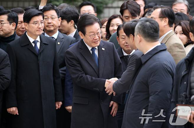 이재명 더불어민주당 대표가 25일 서울 서초구 중앙지방법원에서 열린 위증교사 혐의 1심 선고 공판에 출석하며 동료 의원들과 악수하고 있다. 2024.11.25/뉴스1 ⓒ News1 사진공동취재단