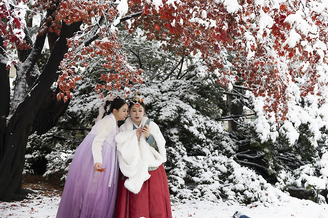 한국 전통 한복을 입은 관광객들이 27일 눈 덮인 서울 경복궁에서 사진을 찍고 있다