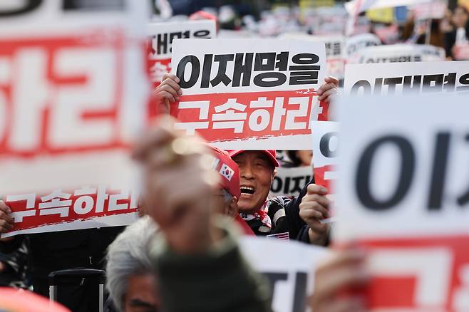 더불어민주당 이재명 대표의 위증교사 사건 1심 선고를 앞둔 25일 보수 단체가 서울 서초구 서울중앙지방법원 인근에서 이 대표 법정 구속 촉구 기자회견을 열자 참가자들이 손팻말을 들고 있다. /연합뉴스