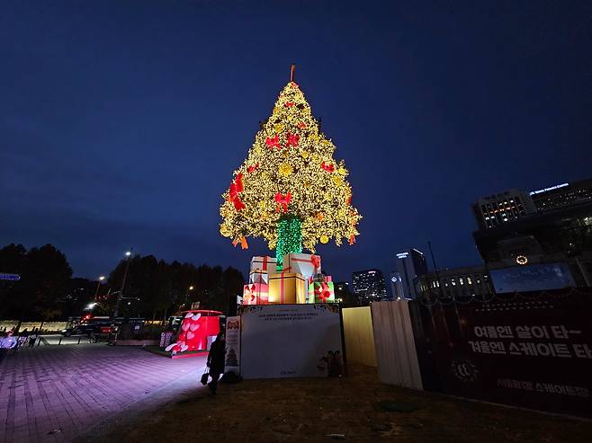 지난 18일 점등식을 가진 서울광장 성탄트리. 트리의 높이는 19m로 노란 트리 조명에 빨간 리본 장식과 하단에는 사랑의 선물 박스로 장식됐다. 리본은 국민을 하나로 묶는 화합의 의미로 하단의 선물 박스는 고통  받는 이웃들에게 전해질 예수 그리스도의 사랑이 선물을 의미한다./전기병 기자