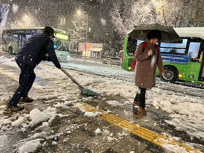 서울 등 중부 지역에 많은 눈이 내린 27일 오전 서울 경복궁역 인근에서 한 시민이 눈을 치우고 있다. 연합뉴스