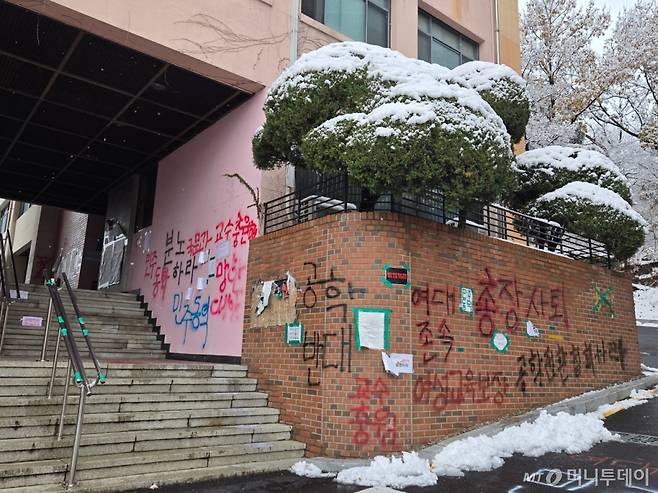 27일 인문관 건물 외벽과 벽돌 담장에 '여성교육보장', '공학전환 철회하라' 등 글씨가 래커로 쓰여있는 모습/사진=이혜수 기자