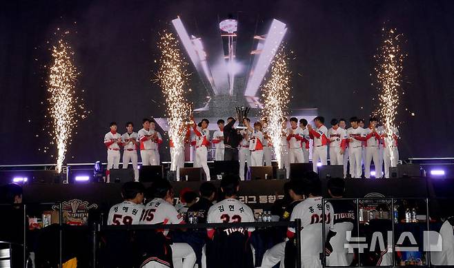 [광주=뉴시스] 변재훈 기자 = 30일 오후 광주 서구 김대중컨벤션센터에서 열린 'KIA 타이거즈 V12 팬 페스트'에 참석한 이범호 감독과 선수단이 정규시즌 우승트로피와 한국시리즈 우승 트로피를 들어올리고 있다. 2024.11.30. wisdom21@newsis.com