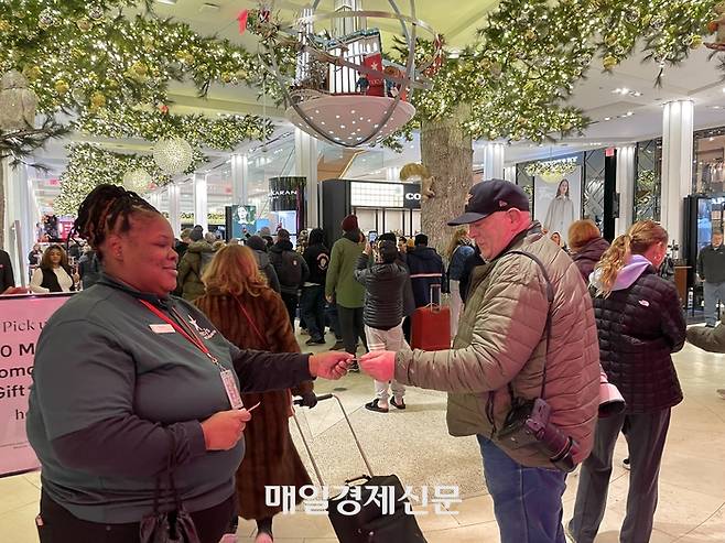 미국 최대 쇼핑 대목 블랙프라이데이인 지난 29일(현지시간) 새벽 6시 맨해튼 한복판 메이시스 헤럴드 스퀘어점이 문을 연 직후 직원이 손님들에게 10달러 짜리 백화점 상품권을 무료로 나누어 주고 있다.  <사진=윤원섭 특파원>