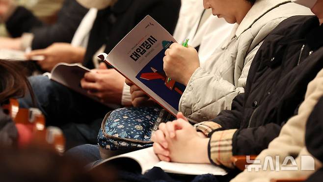 [서울=뉴시스] 추상철 기자 = 지난달 17일 서울 영등포구 영등포아트홀에서 열린 '2025학년도 대입정시 지원전략 설명회'에서 학부모들이 정시 모집 관련 책자를 살펴보고 있다. 2024.12.01. scchoo@newsis.com