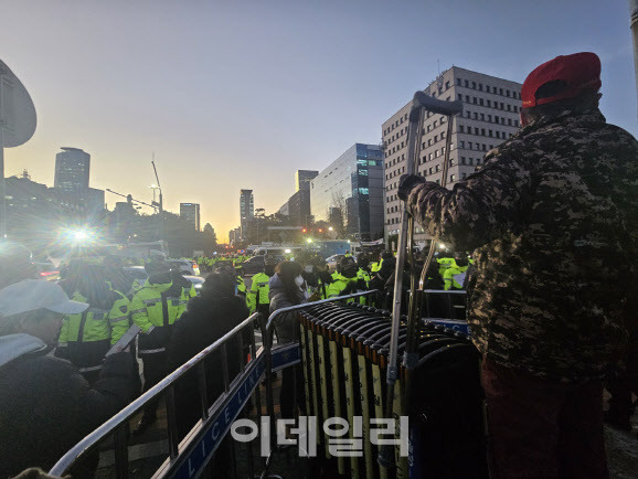 한 시민단체 회원이 여의도 국회 앞에 설치된 철제 펜스 위에 올라가 정치권을 비판하고 있다.(사진= 이영민 기자)