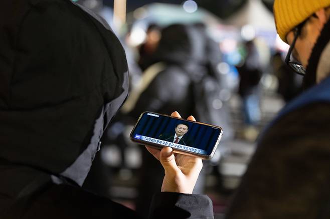 비상계엄 해제 요구 결의안이 국회 본회의에서 통과된 4일 새벽 서울 여의도 국회 인근에서 한 시민이 윤석열 대통령의 비상계엄 해제 관련 담화를 지켜보고 있다. / 뉴스1