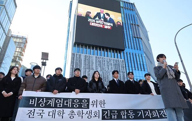 비상계엄대응을 위한 전국 대학 총학생회 긴급 합동 기자회견이 서울 서대문구 신촌 스타광장에서 열린 6일 오전 참석자들 너머로 전광판에 윤석열 대통령 모습이 나오고 있다. 김혜윤 기자 unique@hani.co.kr