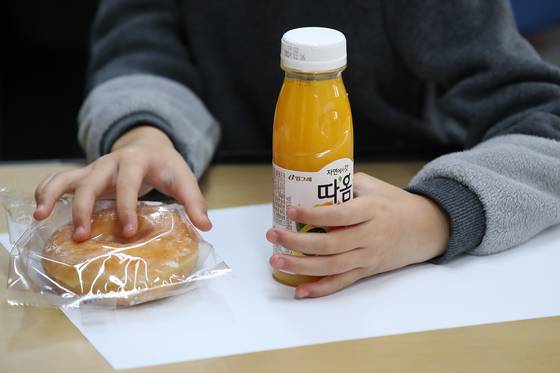 An elementary school student gets bread and juice instead of a proper meal in Daegu on Friday after a strike by a labor union representing irregular workers, including those who handle meals at schools. [YONHAP]