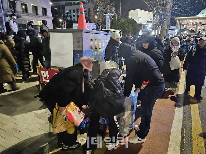 7일 밤 서울 영등포구 국회 앞에서 집회를 마친 시민들이 자발적으로 쓰레기를 정리하고 있다. (사진=김형환 기자)