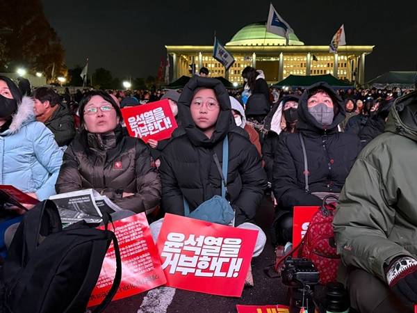▲7일 오후 국민의힘 의원들이 윤석열 대통령 탄핵소추안 표결을 앞두고 집단으로 국회 본회의장을 빠져나간 후 국회 앞 국회대로에서 생중계로 이를 지켜보던 시민들의 한숨섞인 한탄과 분노가 쏟아졌다. 한참동안 멍하니 생중계 화면을 바라보는 시민들도 있었다. 사진=윤유경 기자.