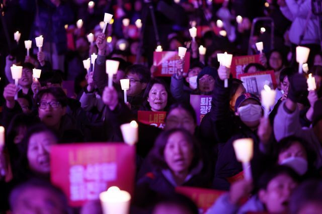 지난 4일 오후 서울 동화면세점 앞에서 전국민주노동조합총연맹 주최로 열린 ‘내란죄 윤석열 퇴진! 시민촛불’에서 참가자들이 촛불을 들고 있다. 연합뉴스