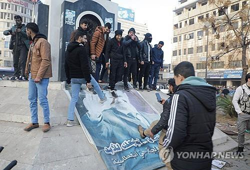 시리아 바샤르 알아사드 대통령의 포스터를 시민들이 뜯어내고 있다. [로이터 연합뉴스 자료사진. 재판매 및 DB 금지]